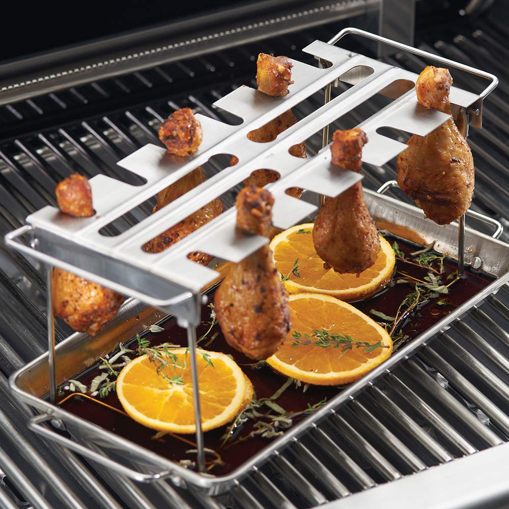 Wing rack with drip pan on grill grates, holding roasted wings and orange slices