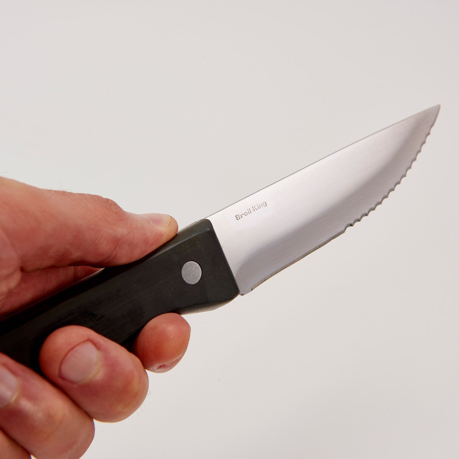 Handheld steak knife with black handle and stainless blade with serrated edge
