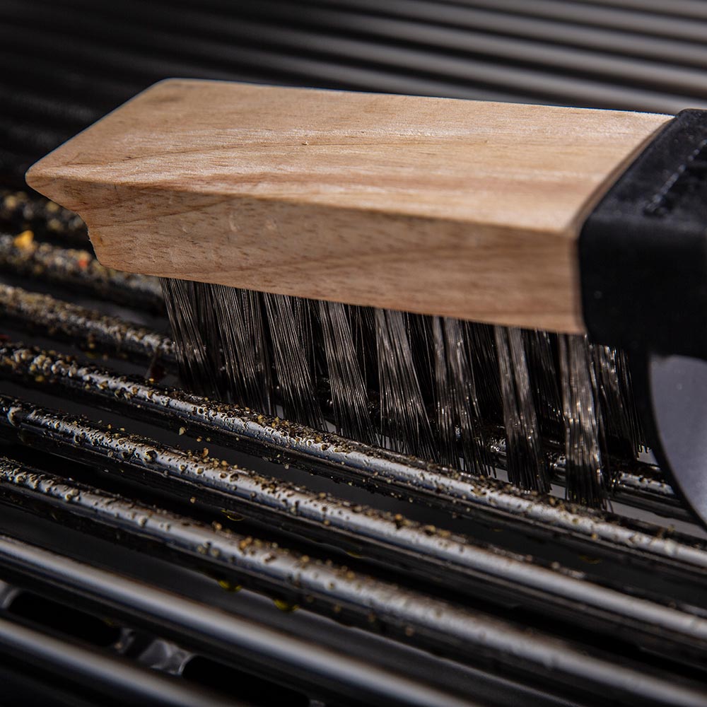 Grill brush bristles cleaning a grill grate