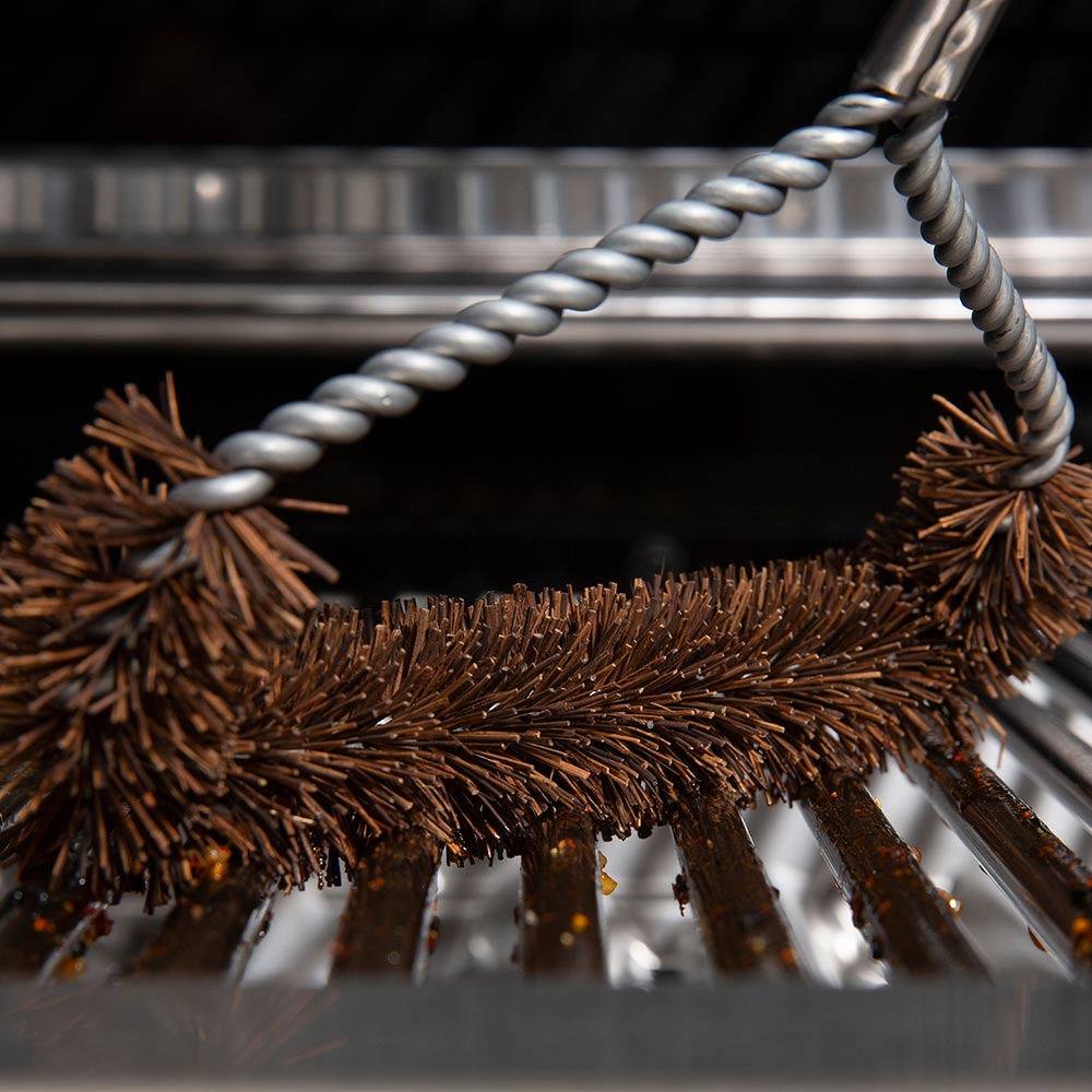 Tri-head grill brush bristles scrubbing metal grill grates, with twisted silver wire