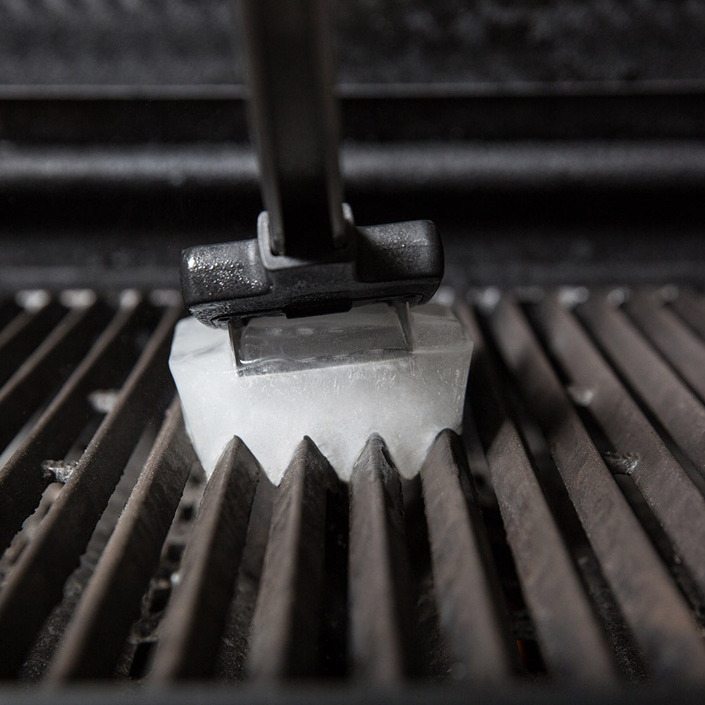 Ice grill brush scraping a hot grill grate with an ice block
