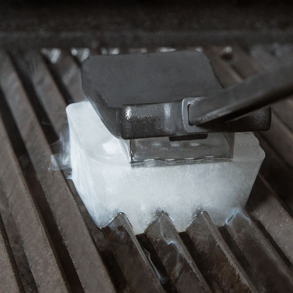 Ice grill brush lifting ice-covered residue from grill grates