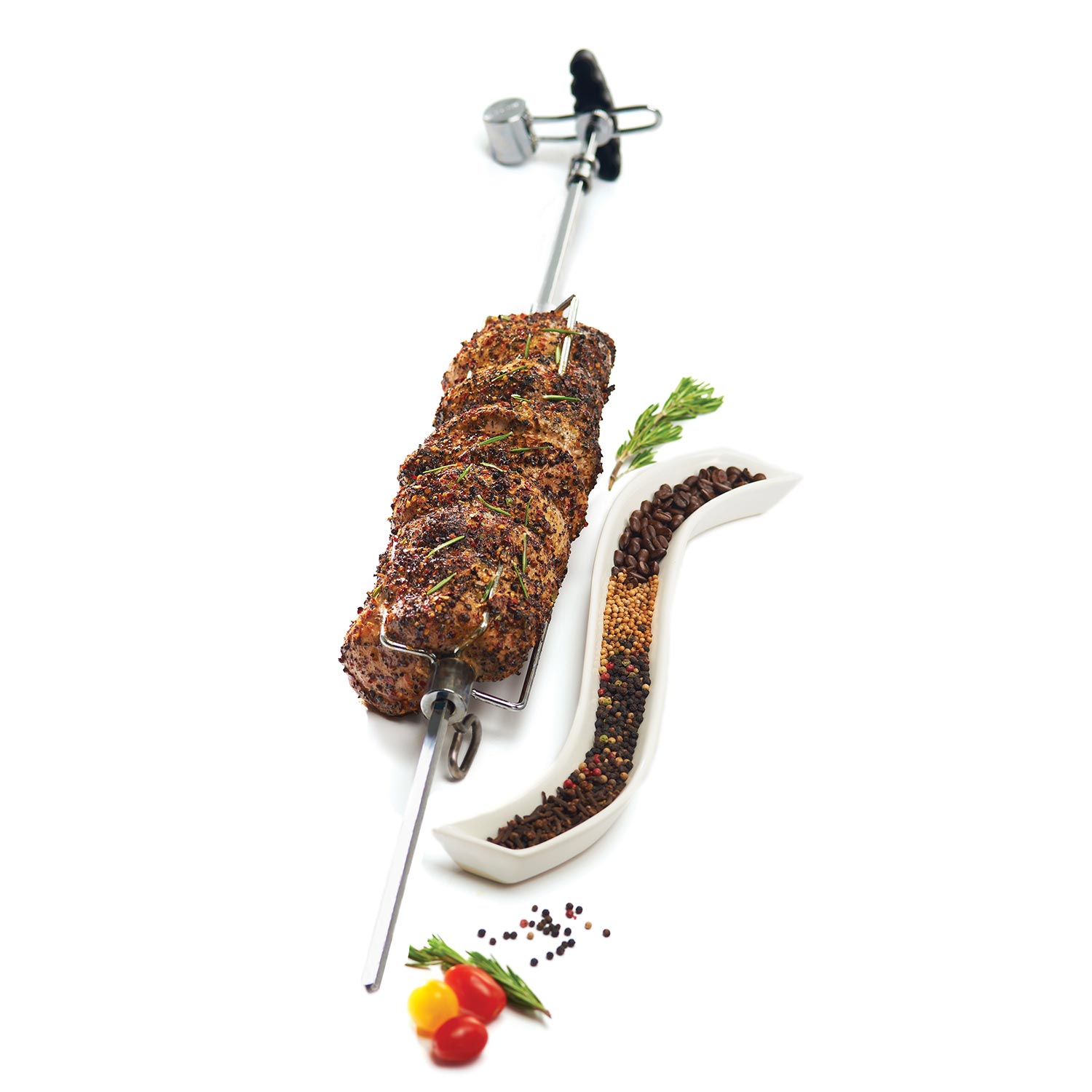 Rotisserie spit with herb-seasoned meat and forks; vegetables and spices beside
