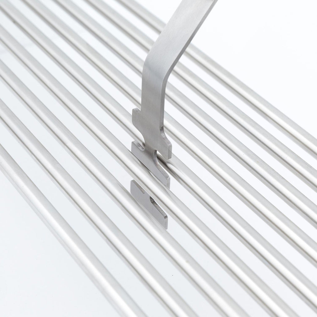 Broil King grid lifter tool with silver head on white grill grates
