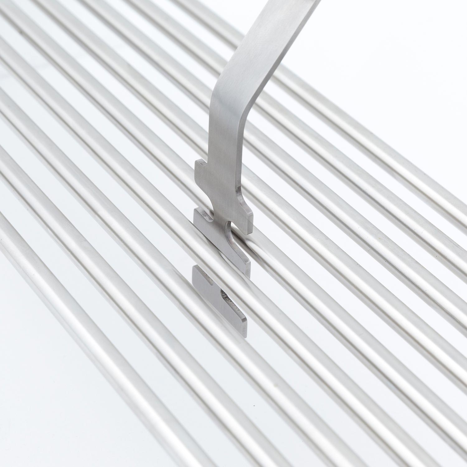 Broil King grid lifter tool with silver head on white grill grates