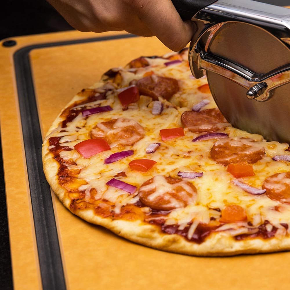 Wood fiber cutting board with a pizza topped with cheese, tomato, and onions