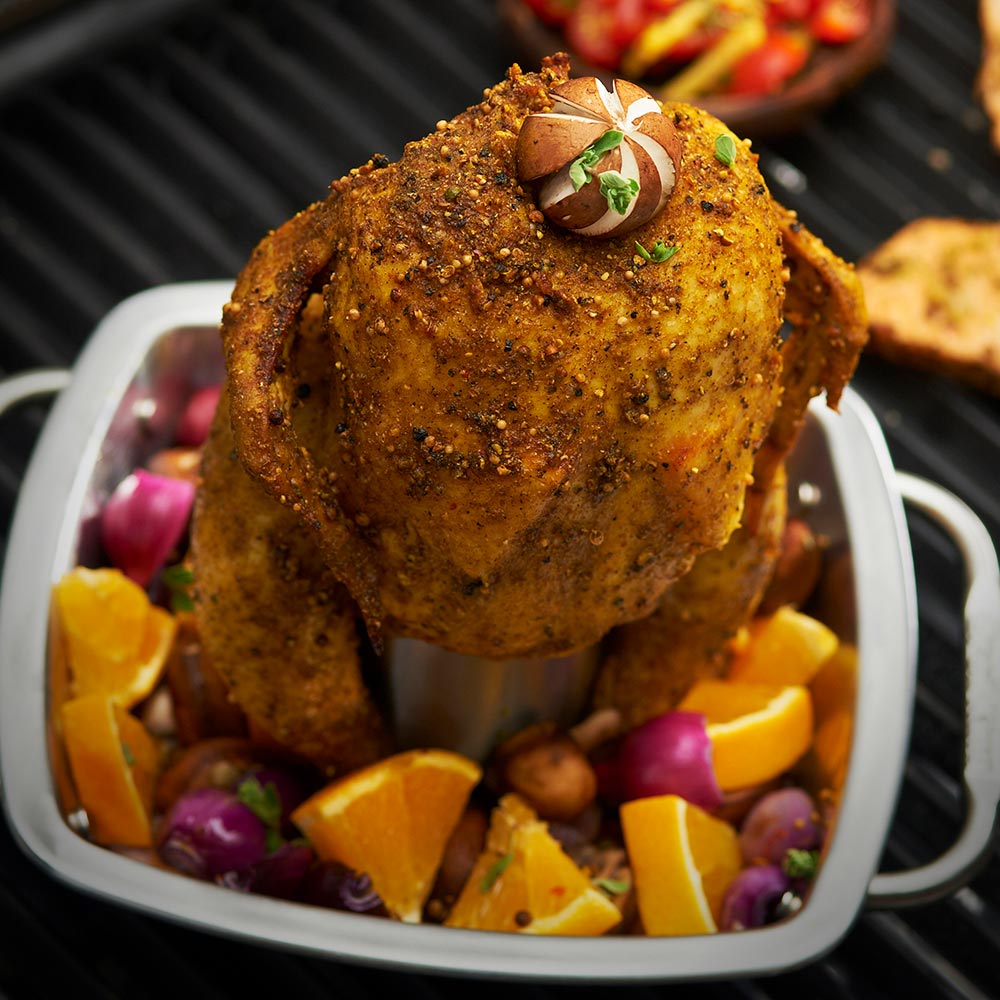 Stainless steel chicken roaster pan with whole roasted chicken and mixed vegetables