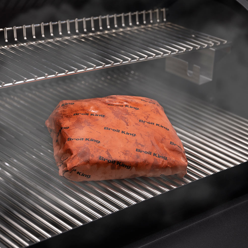 Butcher paper-wrapped meat on grill grates, pink with repeating Broil King logo print