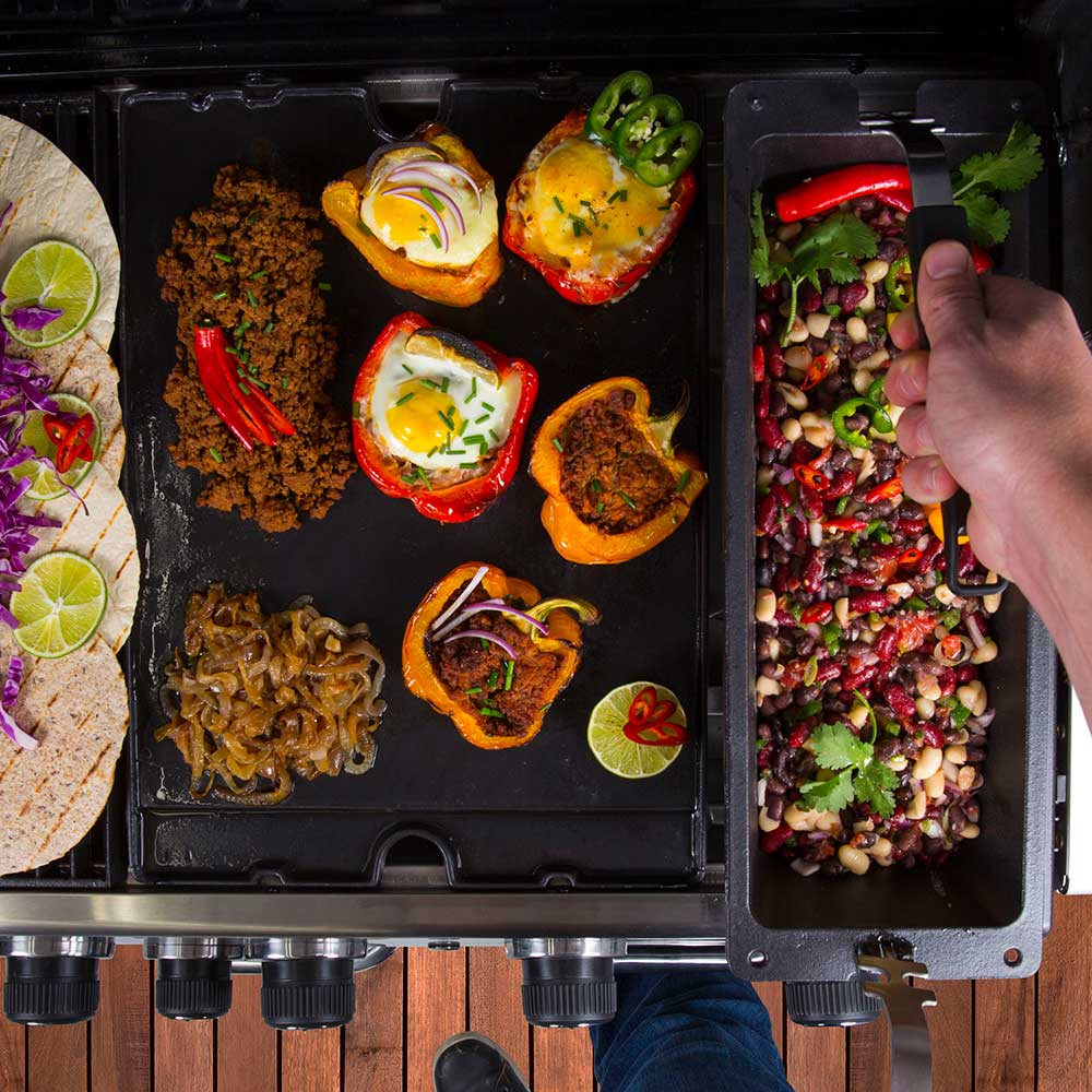 Cast iron rib roaster on grill with assorted grilled foods and added beans