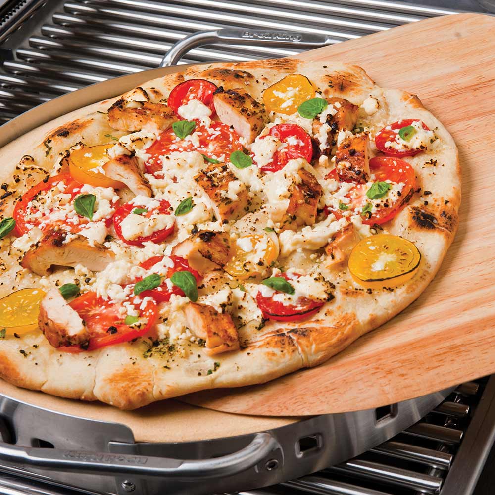 Topped pizza on stainless steel pizza stone grill set, close-up