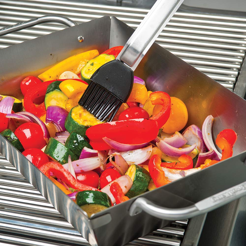 Stainless steel wok filled with mixed vegetables on an open grill grate