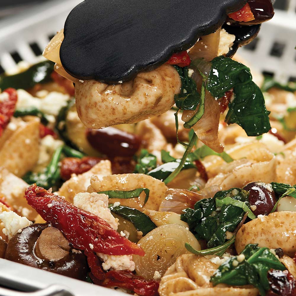 Stainless steel wok grill topper with food close-up on the perforated grate