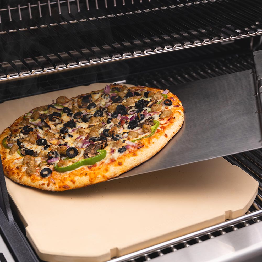 Rectangular pizza stone holding a veggie pizza on a grill rack