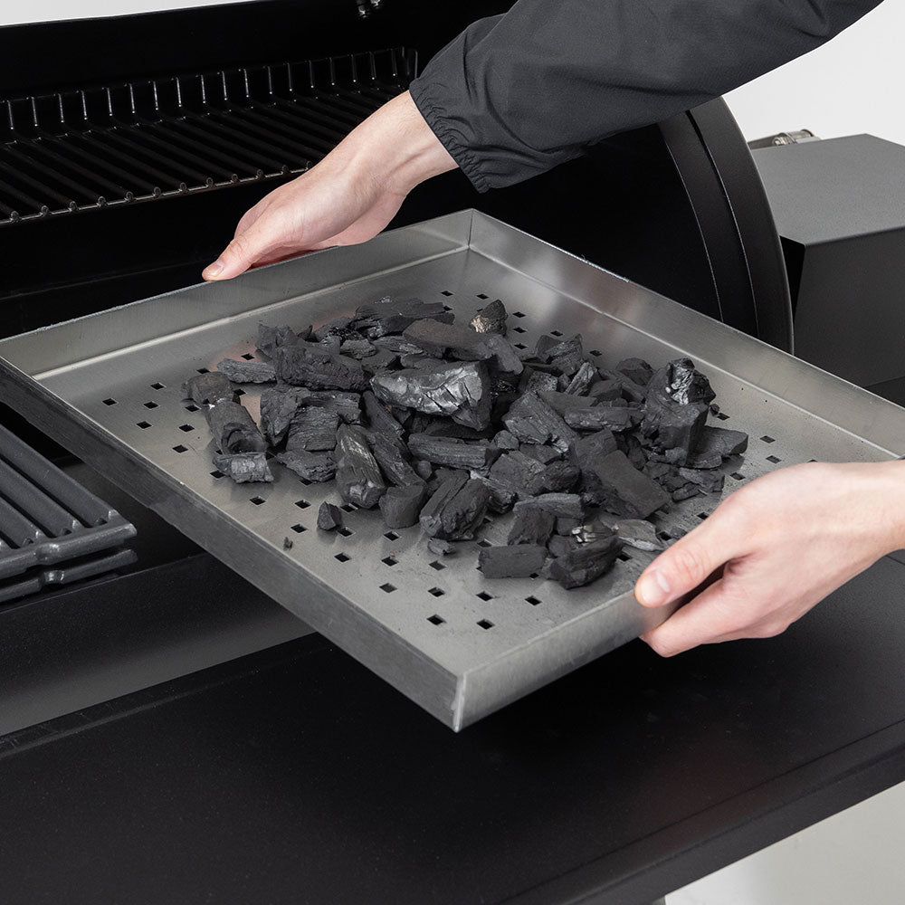 Charcoal smoker firebox tray loading with charcoal briquettes on the grill grate