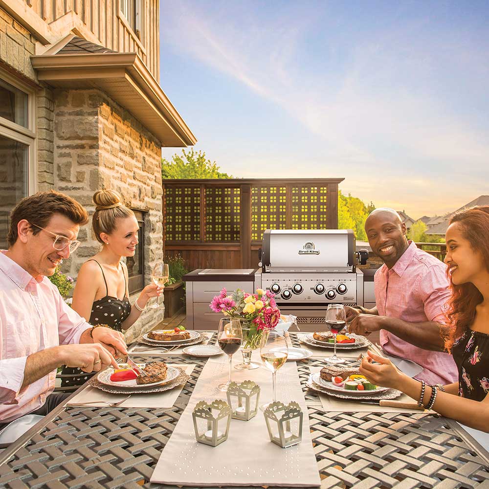 Built-in stainless gas grill at outdoor patio gathering, lid closed
