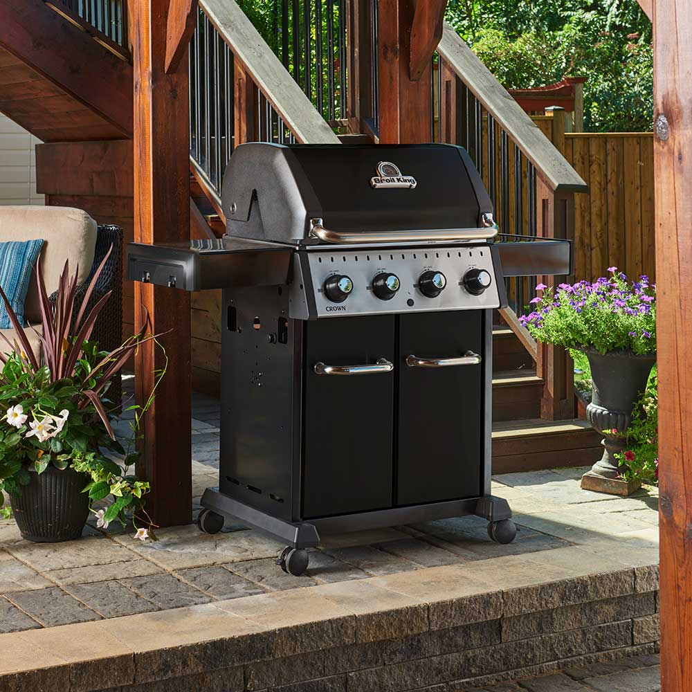 Black 4-burner gas grill on patio with open lid and front control knobs