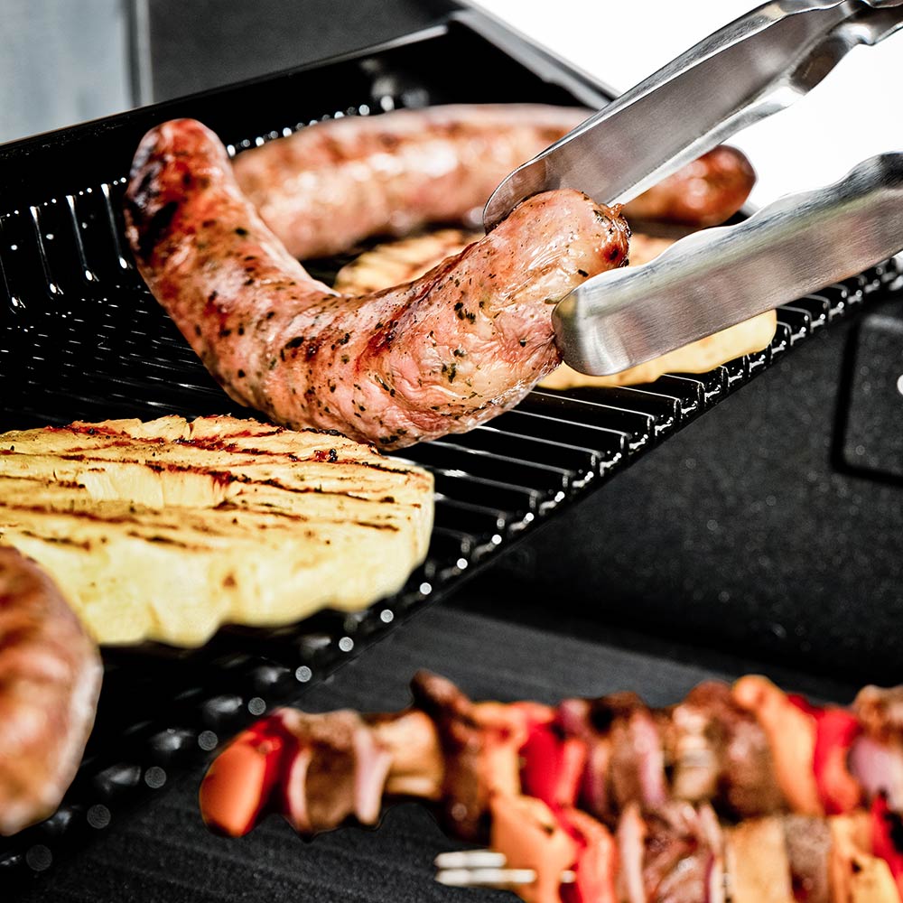 Grill cooking grates with chicken and a fork, food grilling on open burners