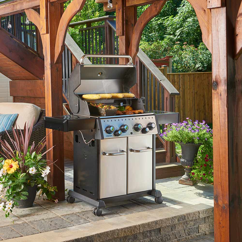 Outdoor stainless steel gas grill on wheels with open hood and front cabinet doors