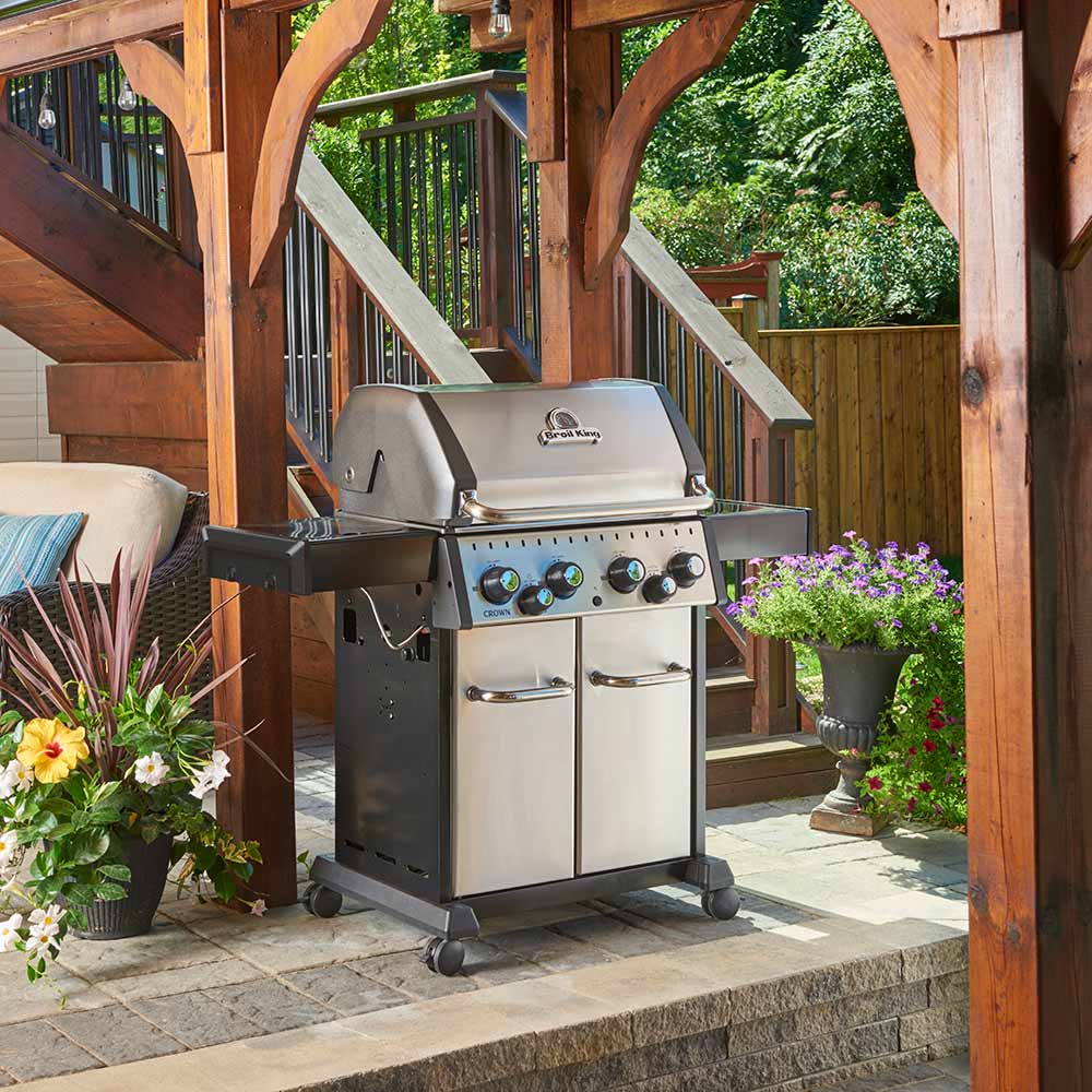 Outdoor stainless steel gas grill on wheels with control knobs and cabinet doors