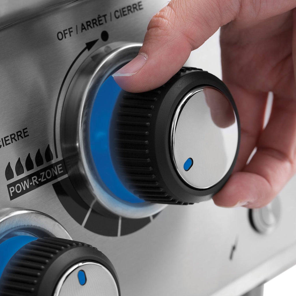 Stainless steel grill control knob being turned with blue indicator