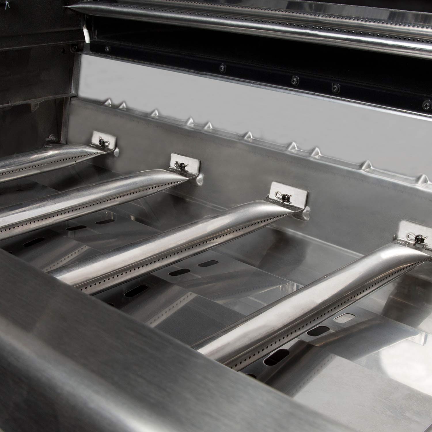Gas grill firebox with angled burner covers and cooking grates visible