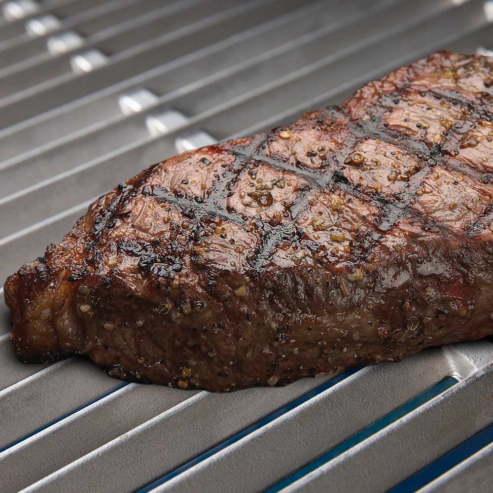 Grilled steak resting on metal grill grates with browned sear