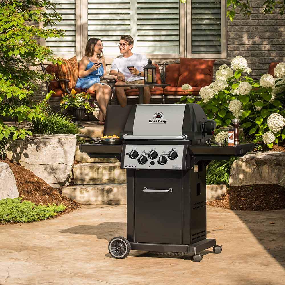 Outdoor 3-burner gas grill with lid closed, front handle, side shelf, and black cart frame