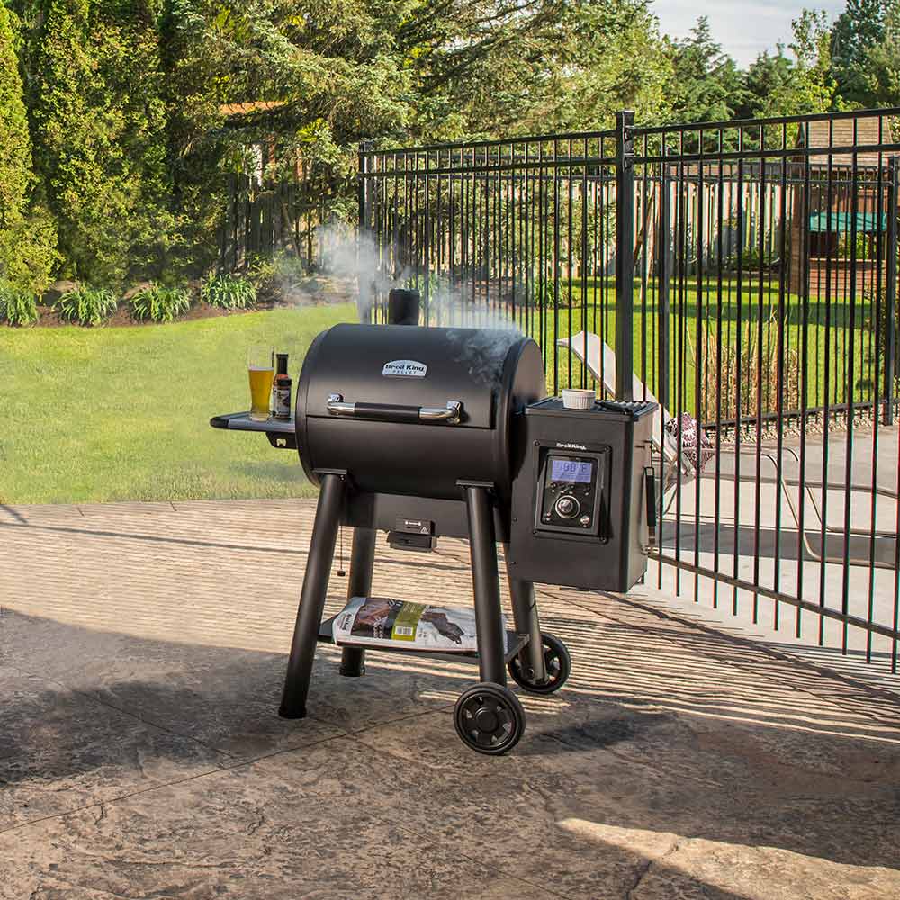 Black pellet smoker and grill on patio deck with front control panel and wheels