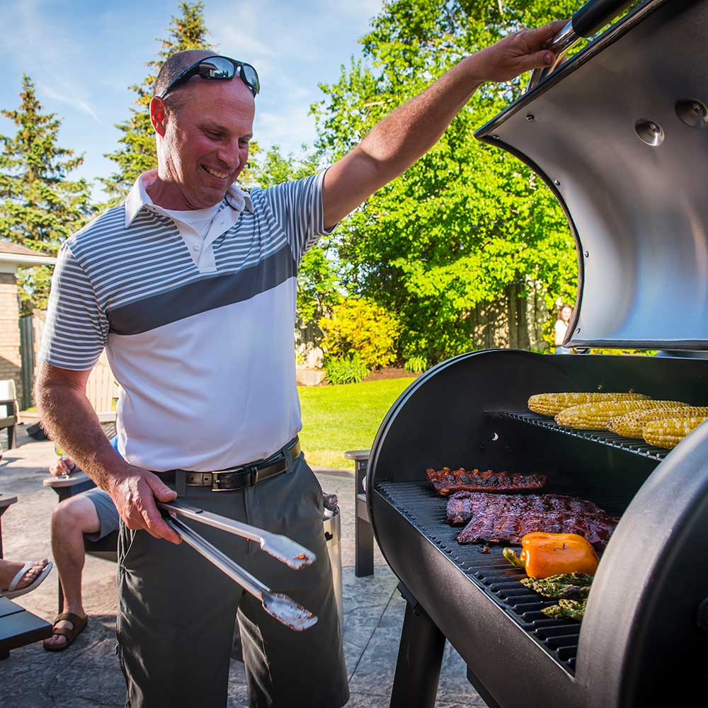 Pellet smoker and grill with lid open, food cooking on the grill grates