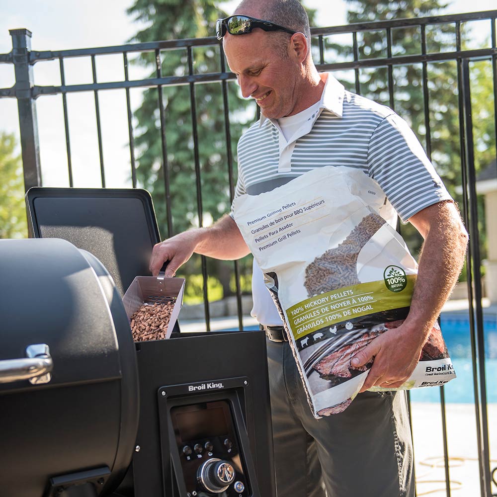 Pellet smoker and grill with side control panel while pellets are added