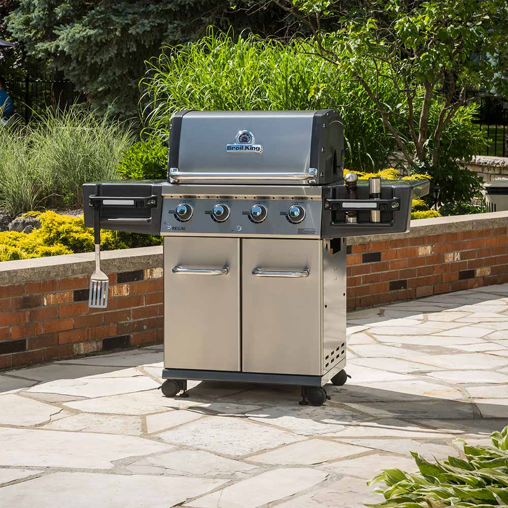 Freestanding gas grill with lid closed, stainless steel panels and four burner control knobs.