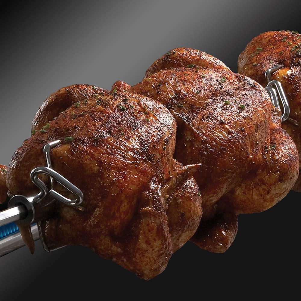 Rotisserie chicken roasting on a spit inside the grill
