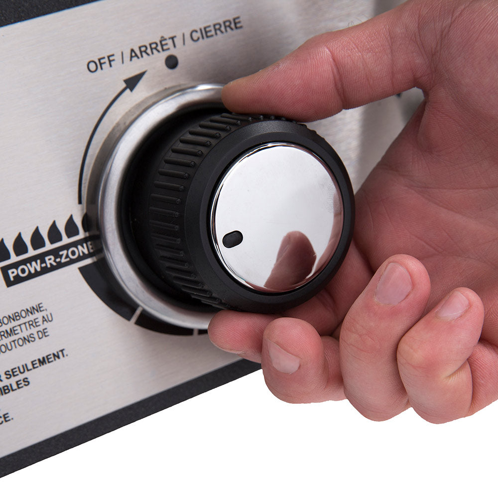 Gas smoker temperature control dial with hand turning the knob on the face panel