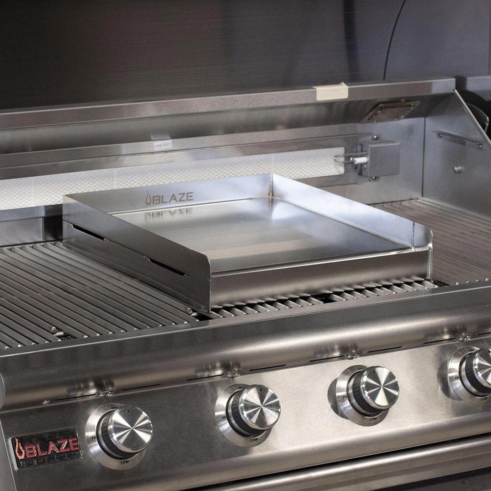 Stainless steel griddle plate mounted on Blaze gas grill above cooking grates.