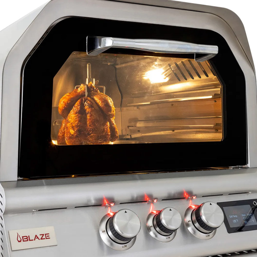 Rotisserie cooking chamber with roasted chicken on skewer inside stainless oven hood
