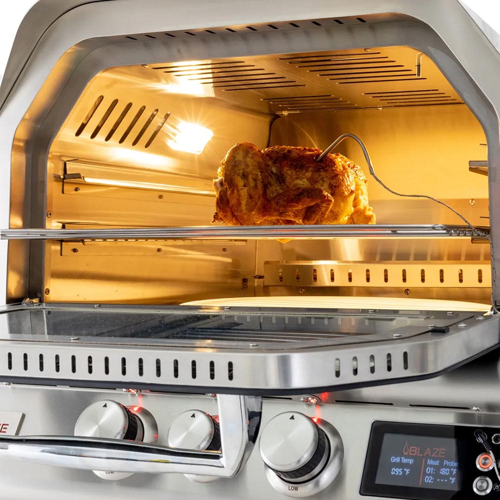 Stainless steel rotisserie oven interior with roasted chicken on spit and metal rails