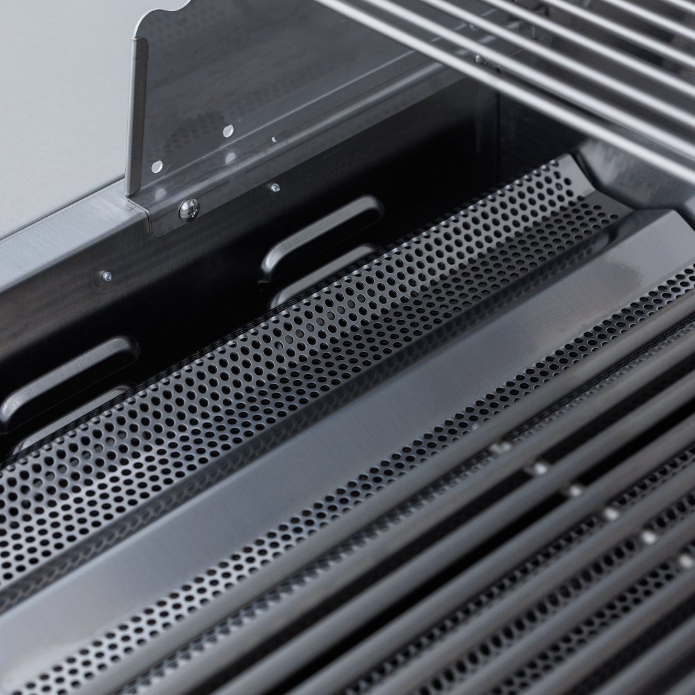 Built-in gas grill open hood showing perforated flame tamers and burner area