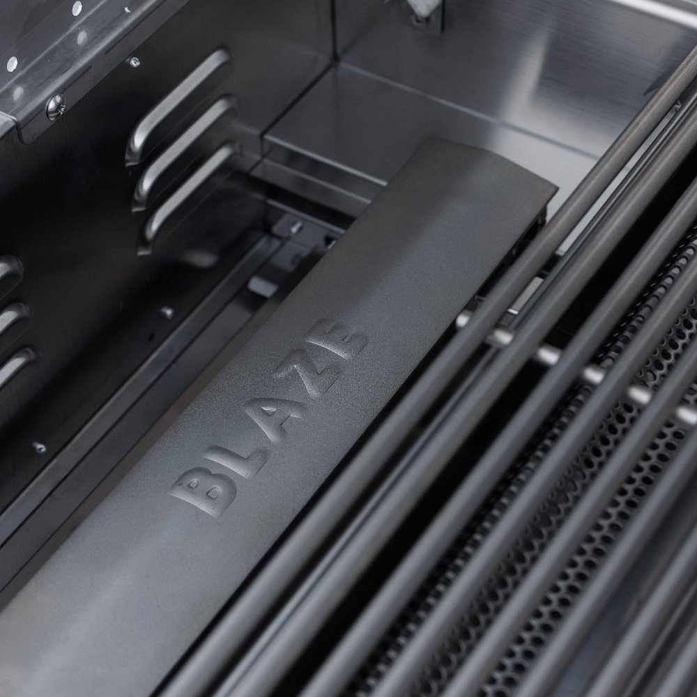 Built-in gas grill interior with stainless burner area and BLAZE embossed panel