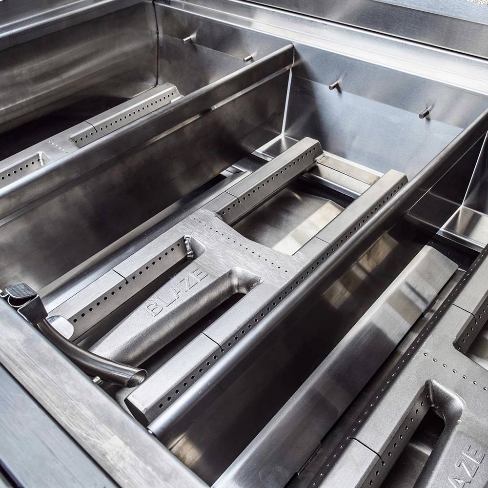 Gas grill cooking box with burner tubes, metal deflectors, and open grate sections