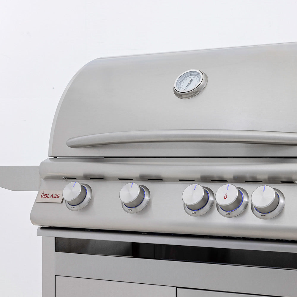 Stainless gas grill lid with thermometer and control knobs, close-up front