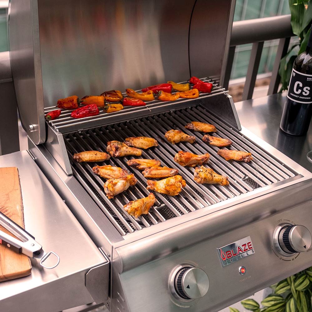 Stainless steel gas grill with food on metal grates and three burners