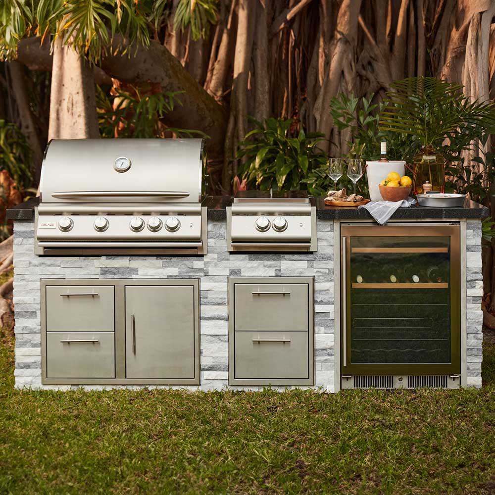 Outdoor stainless gas grill with multiple burner knobs and doors on a base cart