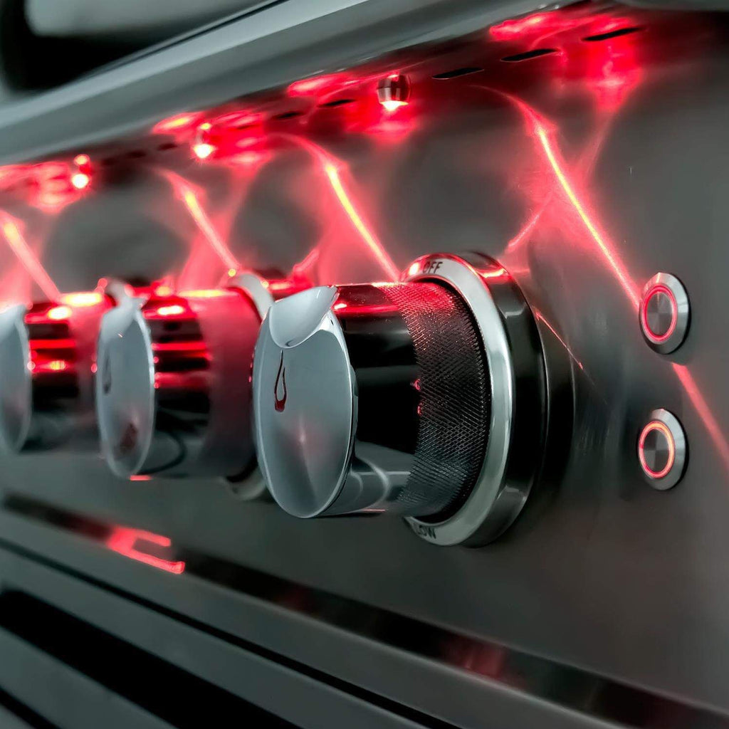 Gas grill burner ignited with red glow under stainless steel hood