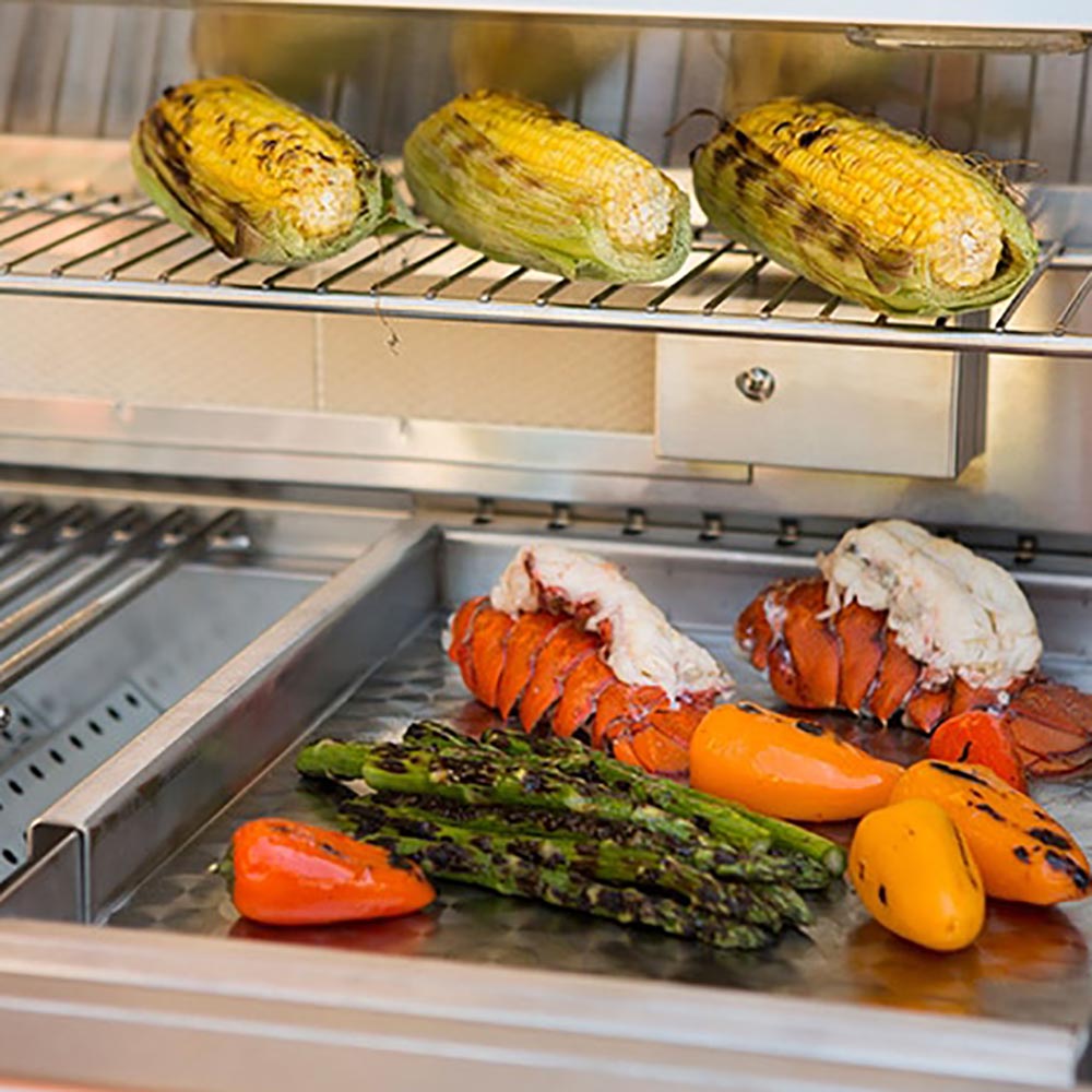 Stainless steel drop-in griddle with grilled vegetables and meats in rectangular tray