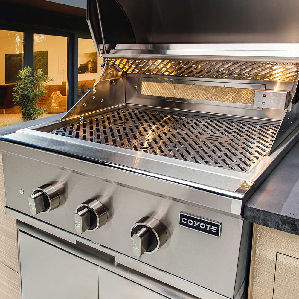 Built-in gas grill with open hood, grill grates, and front burner control knobs