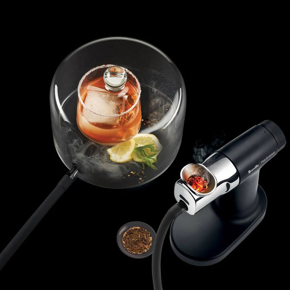 Clear glass cloche dome with food inside and smoking gun with hose