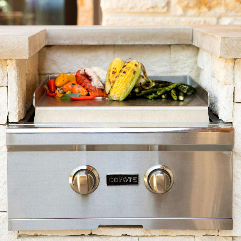 Coyote teppanyaki griddle on stainless grill with control knobs
