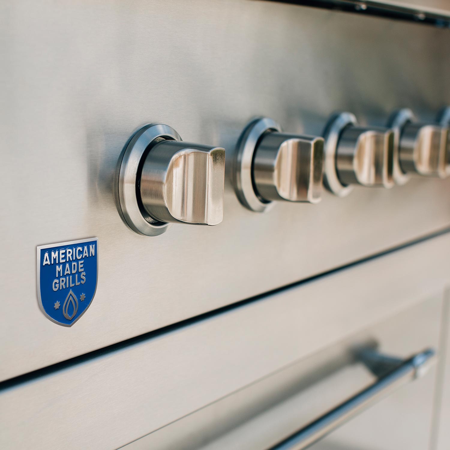 Stainless rotisserie rod assembly with American Made Grills badge on grill panel