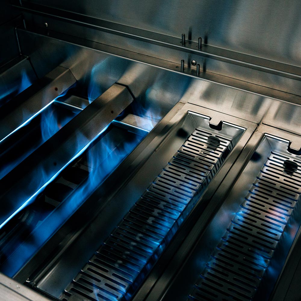 Infrared grill interior with blue-lit burners and multiple slotted heat zones