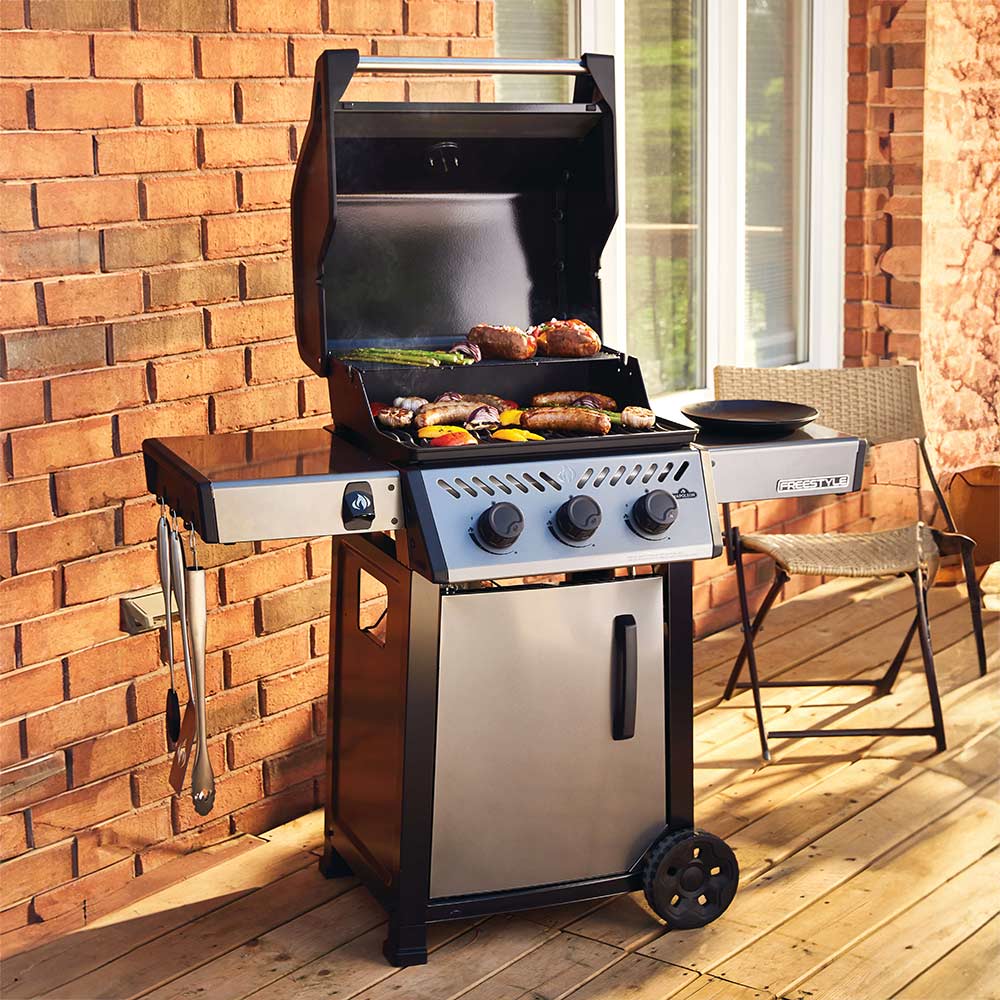 Gas grill on cart with open lid, side shelf, and black cooking surface